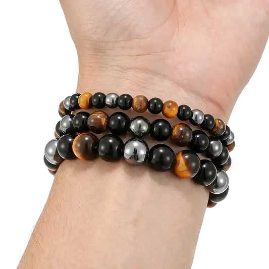 Three stacked bead bracelets combining tiger eye, black obsidian, and hematite beads, worn on a man's wrist.