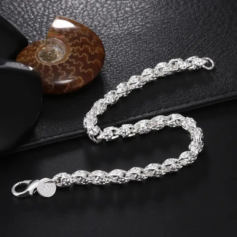 925 sterling silver woven herringbone chain bracelet displayed beside a fossil shell