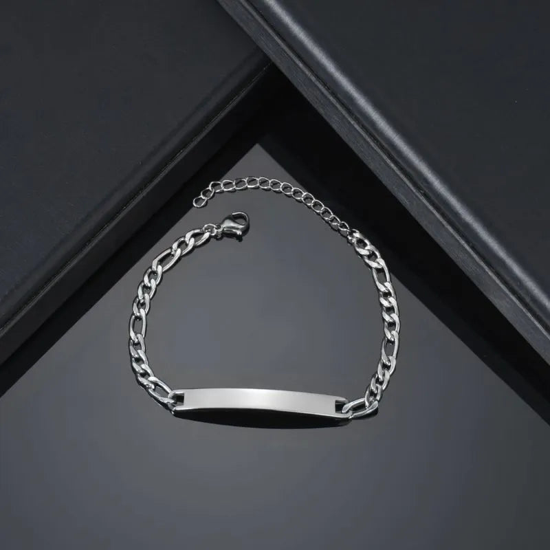 Blank silver figaro-link nameplate bracelet displayed on an angular black gift box