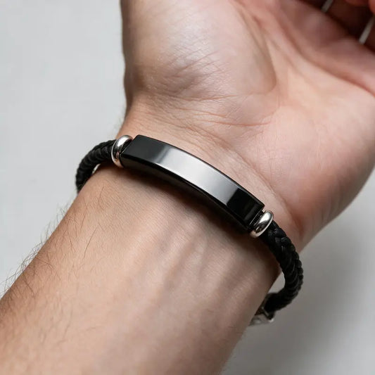Renegade black braided cord bracelet with black ID plate, worn on a man's wrist.