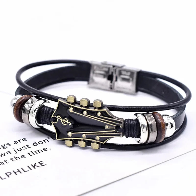 Black leather bracelet with a black enamel guitar headstock charm, on a white background
