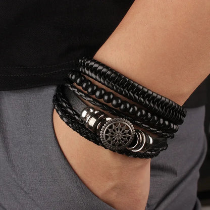 Black leather layered bracelet stack with a mandala charm worn on the wrist, paired with dark clothing.