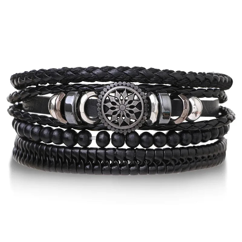 Black leather layered bracelet stack with a mandala charm, black wood beads, and braided strands, on a white background.