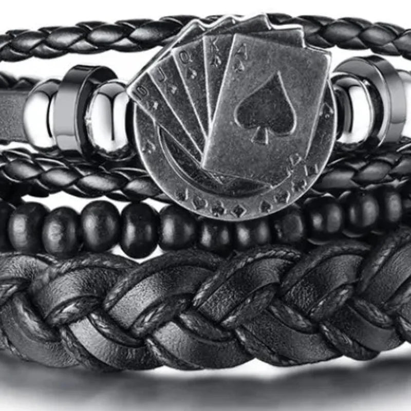 Black leather layered bracelet stack with a silver playing cards charm featuring a spade suit, on a black background.
