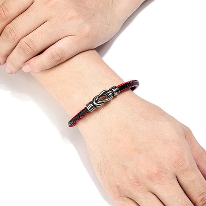 Red and black braided leather bracelet with an infinity-knot clasp worn on the wrist