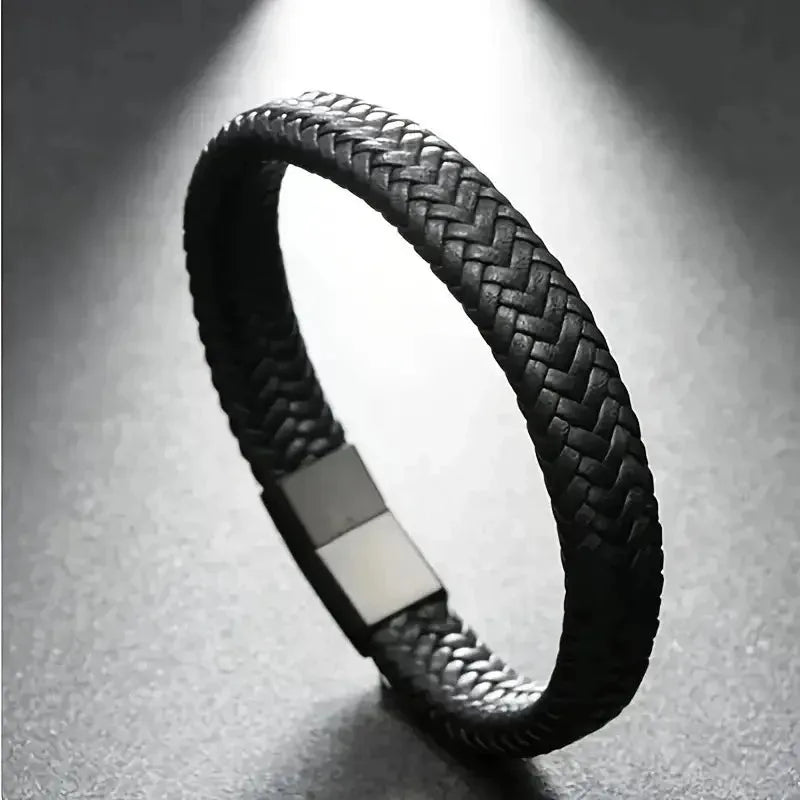 Black braided leather bracelet under dramatic side lighting, showing the rectangular magnetic clasp.