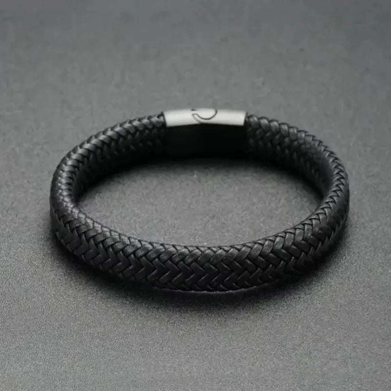 Black braided leather bracelet with a matte black magnetic clasp, on a dark textured surface.