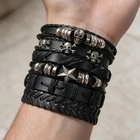 Six-piece black leather bracelet stack with a silver skull bead, skull-and-crossbones charms, and a star bead, worn on a man's wrist.