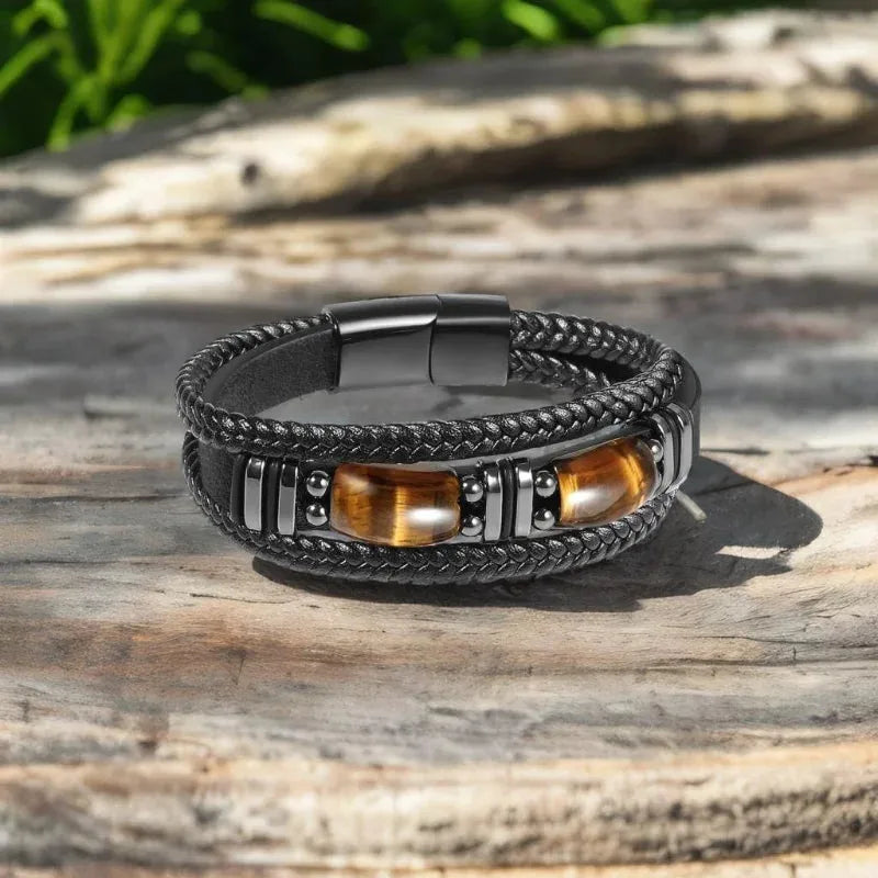 Black leather tiger eye bracelet resting on a weathered wood surface outdoors