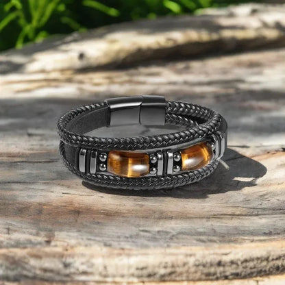 Black leather tiger eye bracelet resting on a weathered wood surface outdoors