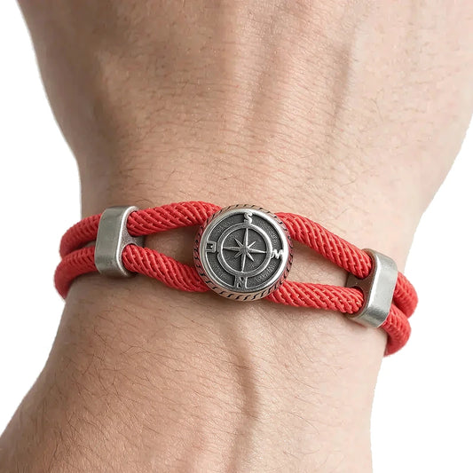 Red double-strand rope bracelet with an antique silver-tone compass charm, worn on wrist