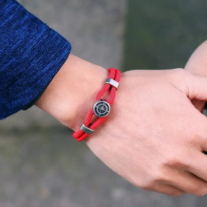 Red compass charm rope bracelet worn on the wrist