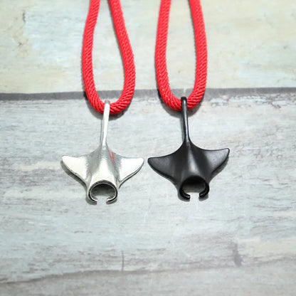Manta ray charms in silver and black finish shown side by side on red cord
