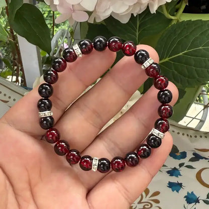 Haven Crackle Glass Bead Bracelet held in hand, deep red bead detail