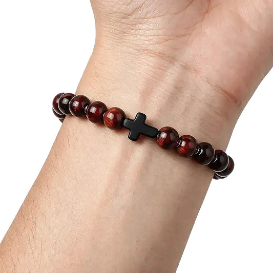 Red tiger eye bead bracelet with a black cross accent bead, worn on a man's wrist.