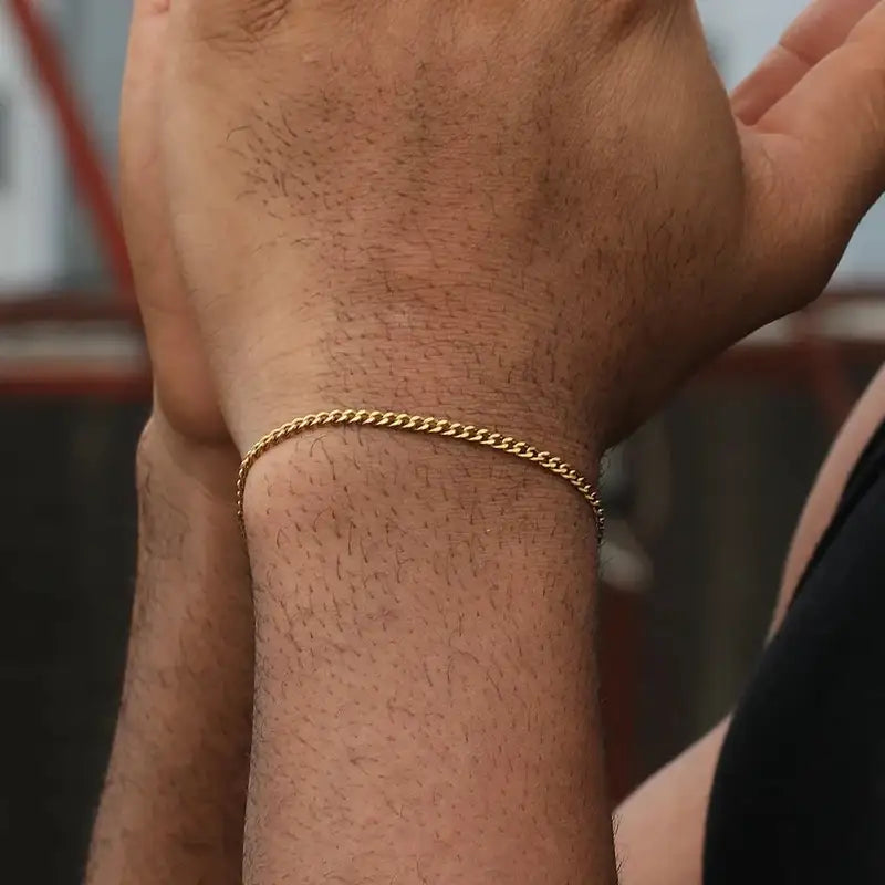 Gold Cuban curb chain bracelet worn on the wrist
