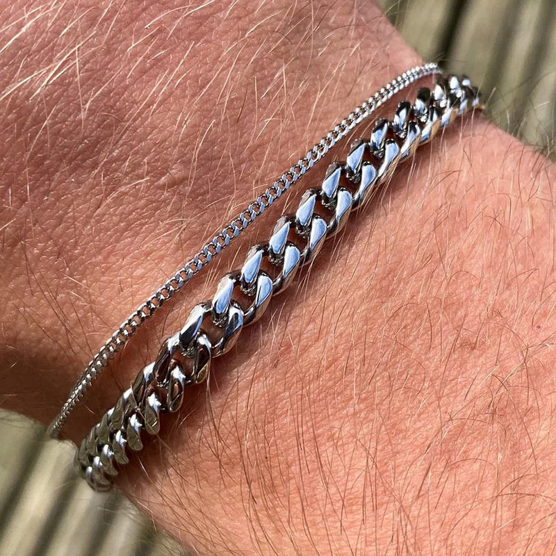 Thin and thick silver Cuban link chain bracelets stacked and worn on the wrist