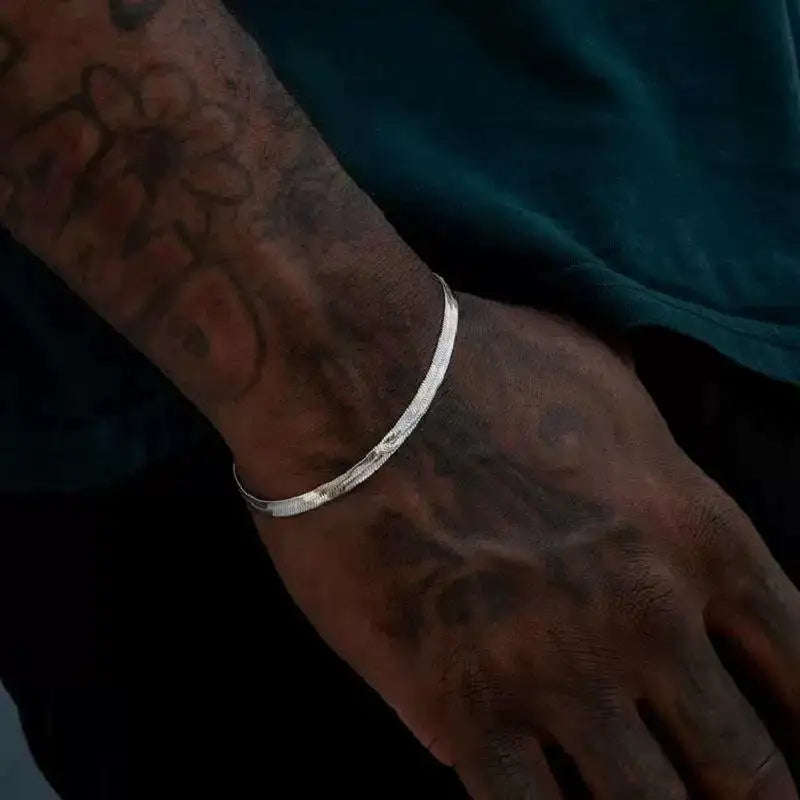 Thin silver flat herringbone chain bracelet worn on the wrist