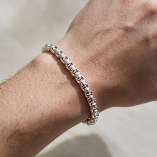 Polished silver rounded box-link rolo chain bracelet worn on the wrist