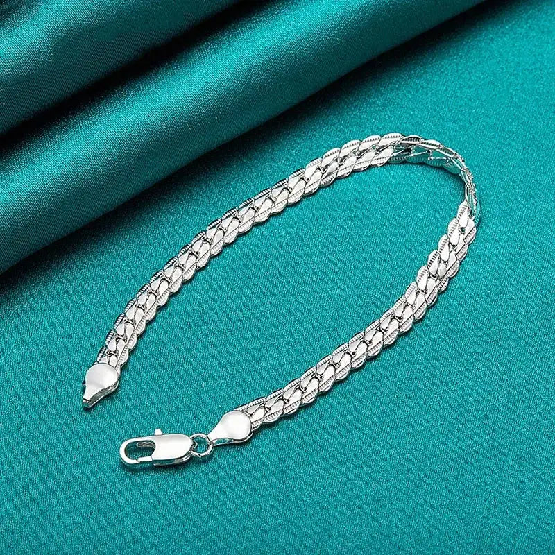 Silver flat curb chain bracelet draped on teal velvet fabric