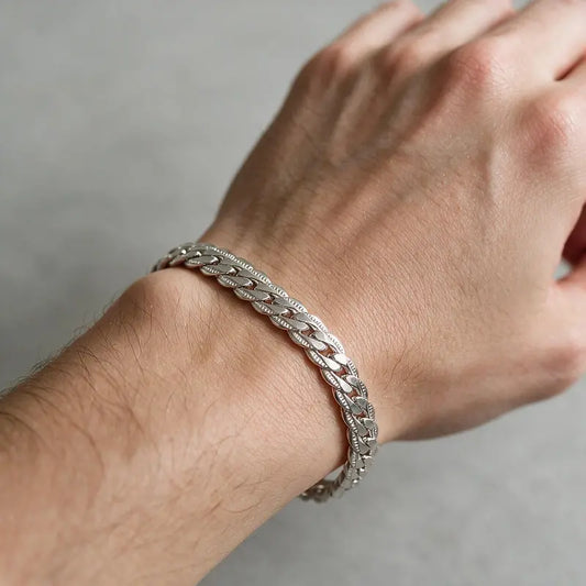 Silver flat curb chain bracelet worn on a man's wrist