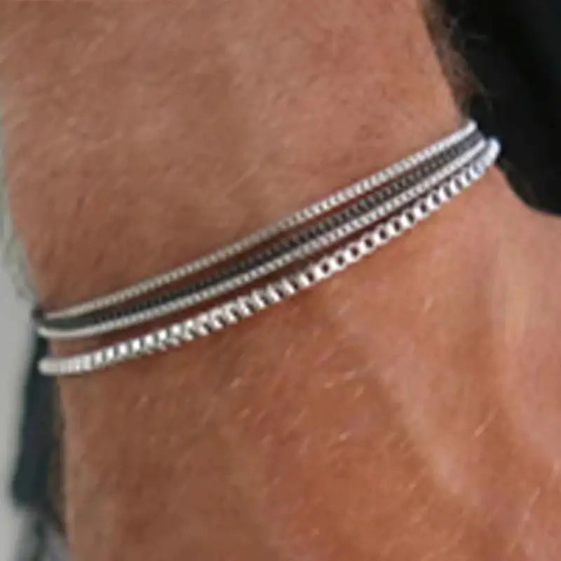 Four silver and black box chain bracelets stacked and worn on the wrist