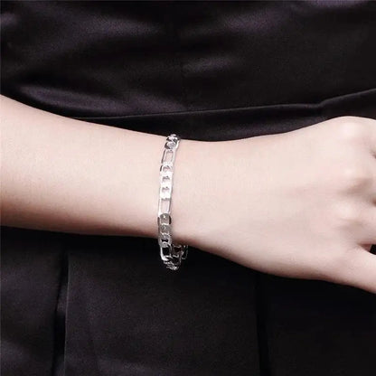 Silver figaro chain bracelet worn on the wrist