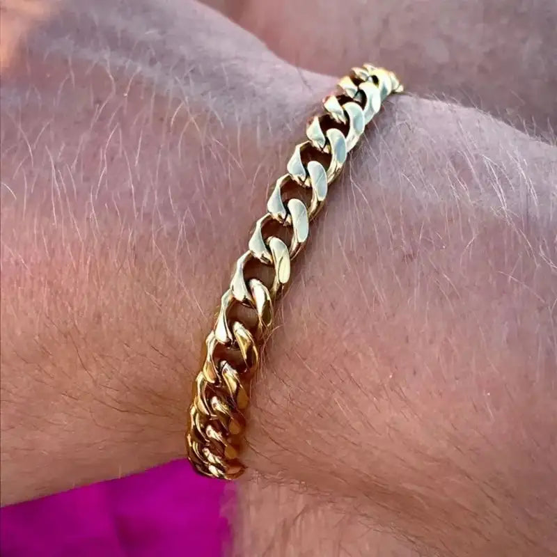 Gold Cuban link chain bracelet worn on the wrist, close-up
