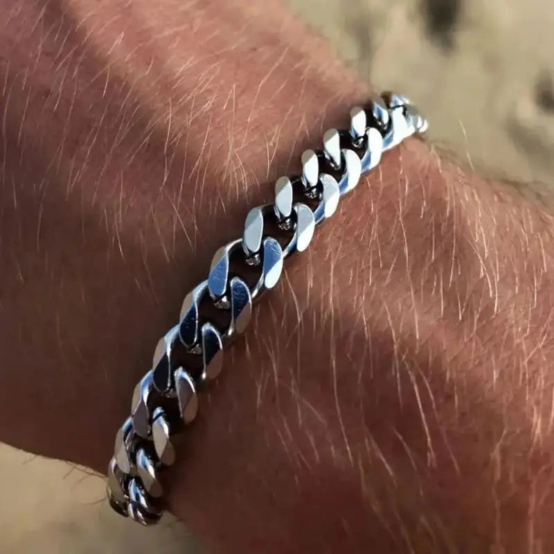 Silver Cuban link chain bracelet worn on the wrist, close-up