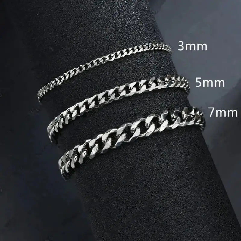 Silver Cuban link chains in 3mm, 5mm and 7mm widths compared on a dark display stand