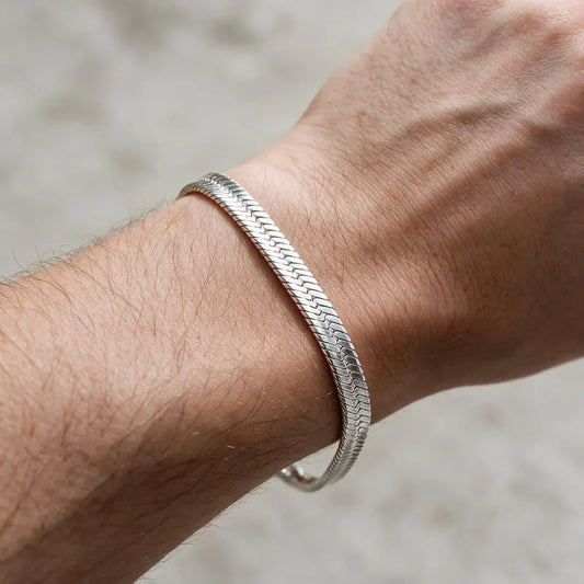 Thin flat silver herringbone chain bracelet worn on the wrist