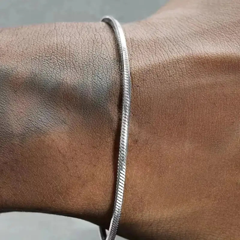 Silver round snake chain bracelet worn on the wrist, close-up on the hand