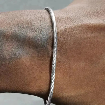 Silver round snake chain bracelet worn on the wrist, close-up on the hand