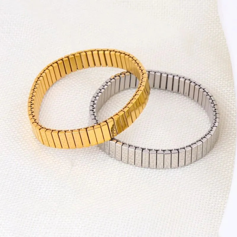Gold and silver stretch bracelets overlapping on white linen fabric
