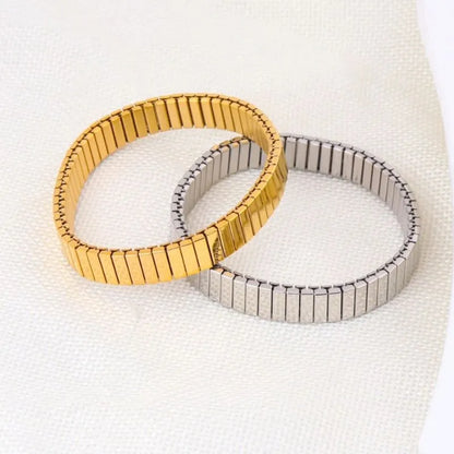 Gold and silver stretch bracelets overlapping on white linen fabric