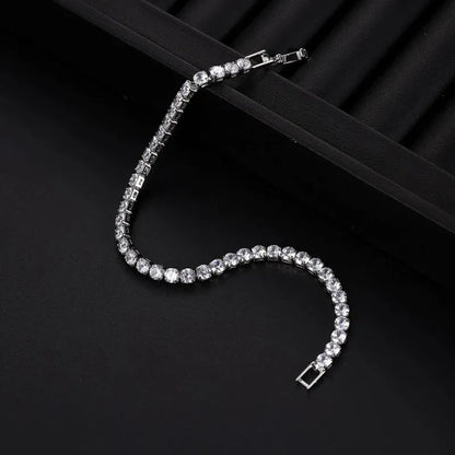 Silver tennis bracelet with clear stones laid in an S-curve on a black ribbed jewellery tray