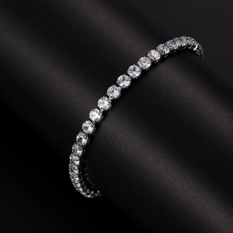 Close-up curved view of the silver tennis bracelet with clear stones against a dark leather-like surface