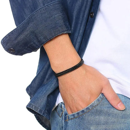 Man's wrist wearing the black wheat chain bracelet, hand in jeans pocket, denim shirt over a white t-shirt