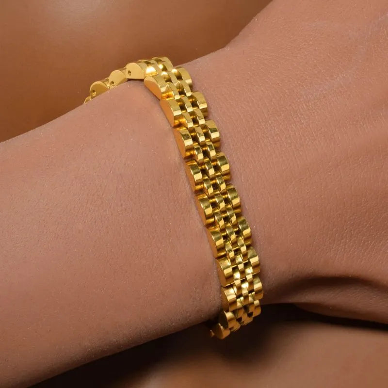 Close-up of the gold watch link bracelet on a bent wrist, showing the link detail against the skin