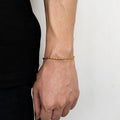 Gold twisted rope chain bracelet worn on the wrist, side profile against a white background.