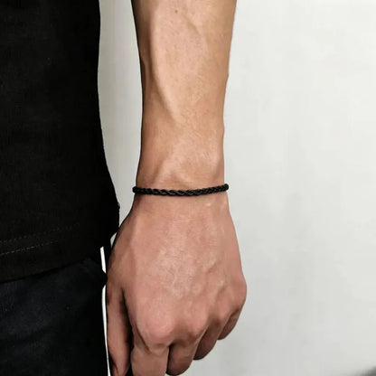 Black twisted rope chain bracelet worn on the wrist, side profile against a white background.