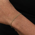 Gold Cuban link bracelet worn on the wrist, shown close-up against a plain black background.