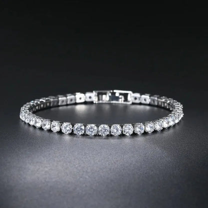 Silver tennis bracelet with round cubic zirconia stones laid in an oval on a dark gradient background, fold-over clasp visible.