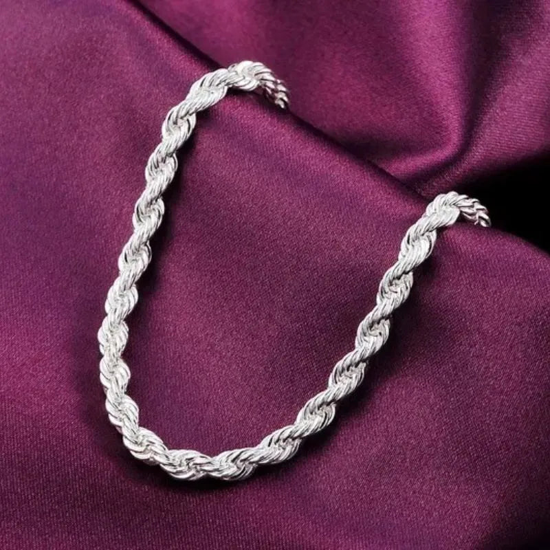 Close-up of the silver twisted rope chain bracelet's unclasped ends, on wine-colored satin fabric.