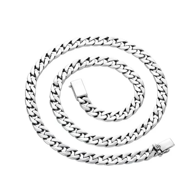 Long silver Cuban-link chain coiled in a spiral on a plain white background.