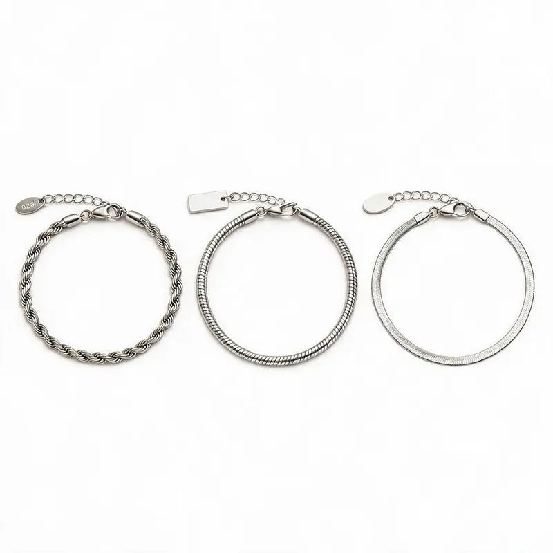 Three silver chain bracelets — twisted rope, snake chain, and flat blade chain — laid out separately with clasp and extension chain closure detail and pendant tags, on a plain white background.
