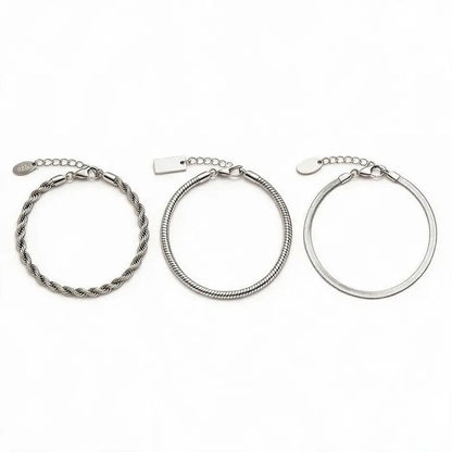 Three silver chain bracelets — twisted rope, snake chain, and flat blade chain — laid out separately with clasp and extension chain closure detail and pendant tags, on a plain white background.