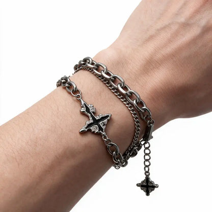 Dark stainless steel cross bracelet worn on wrist, white background