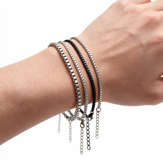 Set of 4 stainless steel box chain bracelets worn on wrist, white background